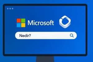 Mavi bir ekran üzerinde, Microsoft logosu ve Microsoft Copilot logosu yan yana yer alıyor. Altında beyaz ve oval köşeli bir arama çubuğu içinde 'Nedir?' yazısı ve sağda büyüteç simgesi bulunuyor. Arayüz, modern ve sade bir tasarımla sunulmuş.